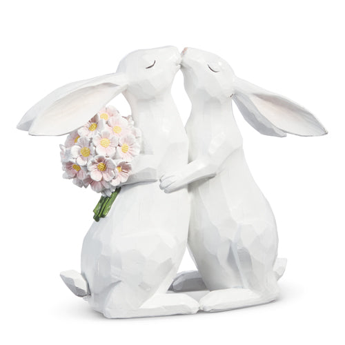 wooden bunny couple figurine that are hugging with a bouquet of flowers behind the back of one bunny