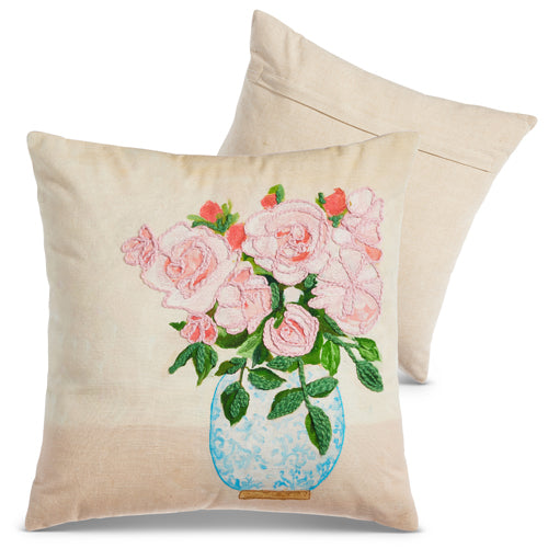 cream colored pillow with bouquet of pink flowers in blue vase