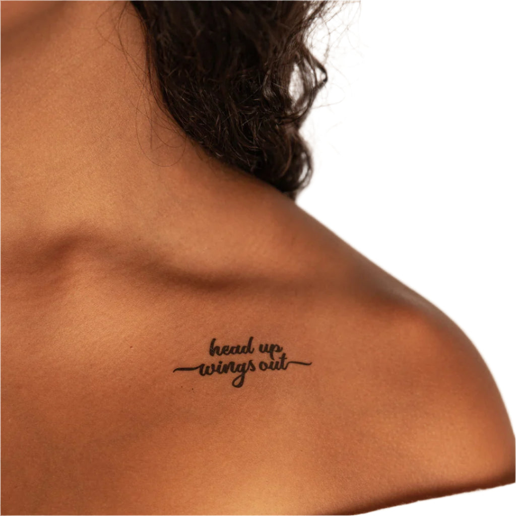 a woman has a tattoo on her shoulder that says head up wings out