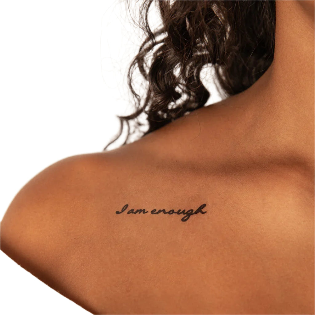 a woman has a tattoo on her shoulder that says i am enough